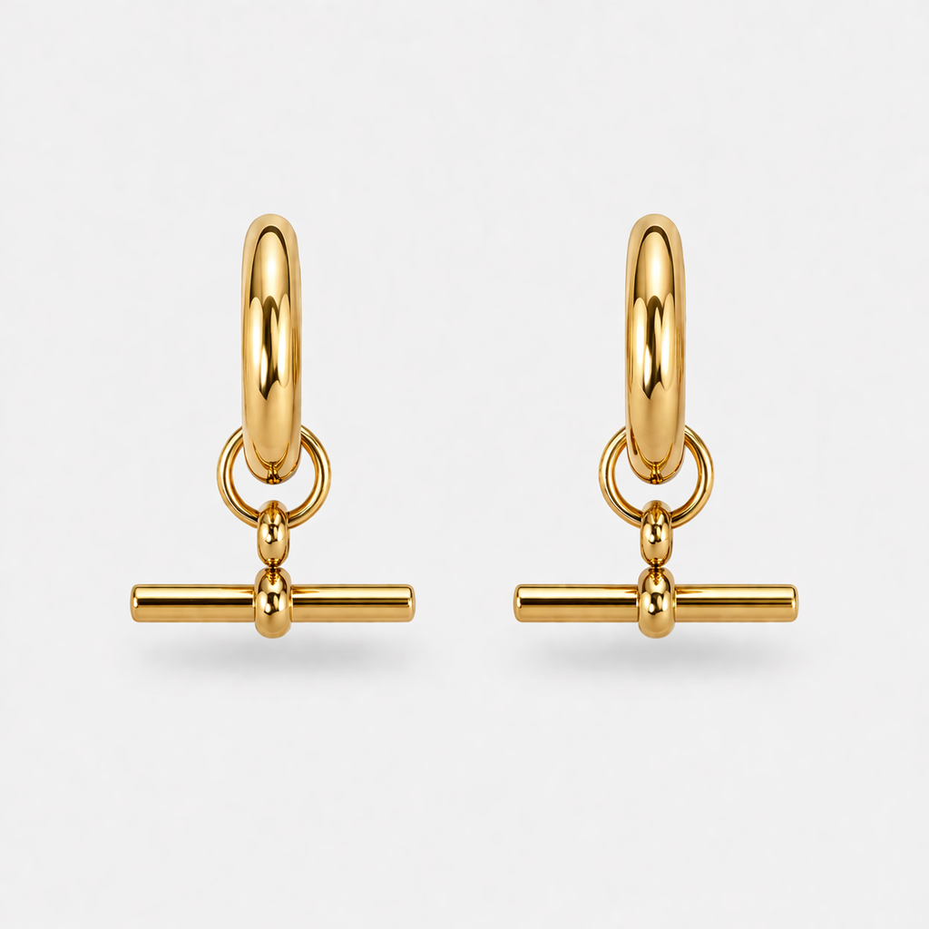 Pair of gold hoop earrings with bar charms on a light gray background