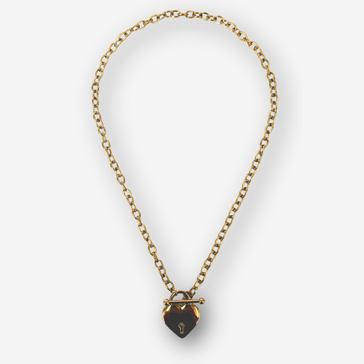 A gold chain necklace with a heart-shaped pendant and a gold toggle clasp, shown on a light gray background.