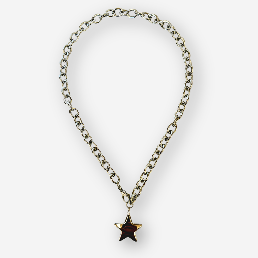 A silver-toned metal chain necklace with a dangling star-shaped pendant, set against a plain light gray background.