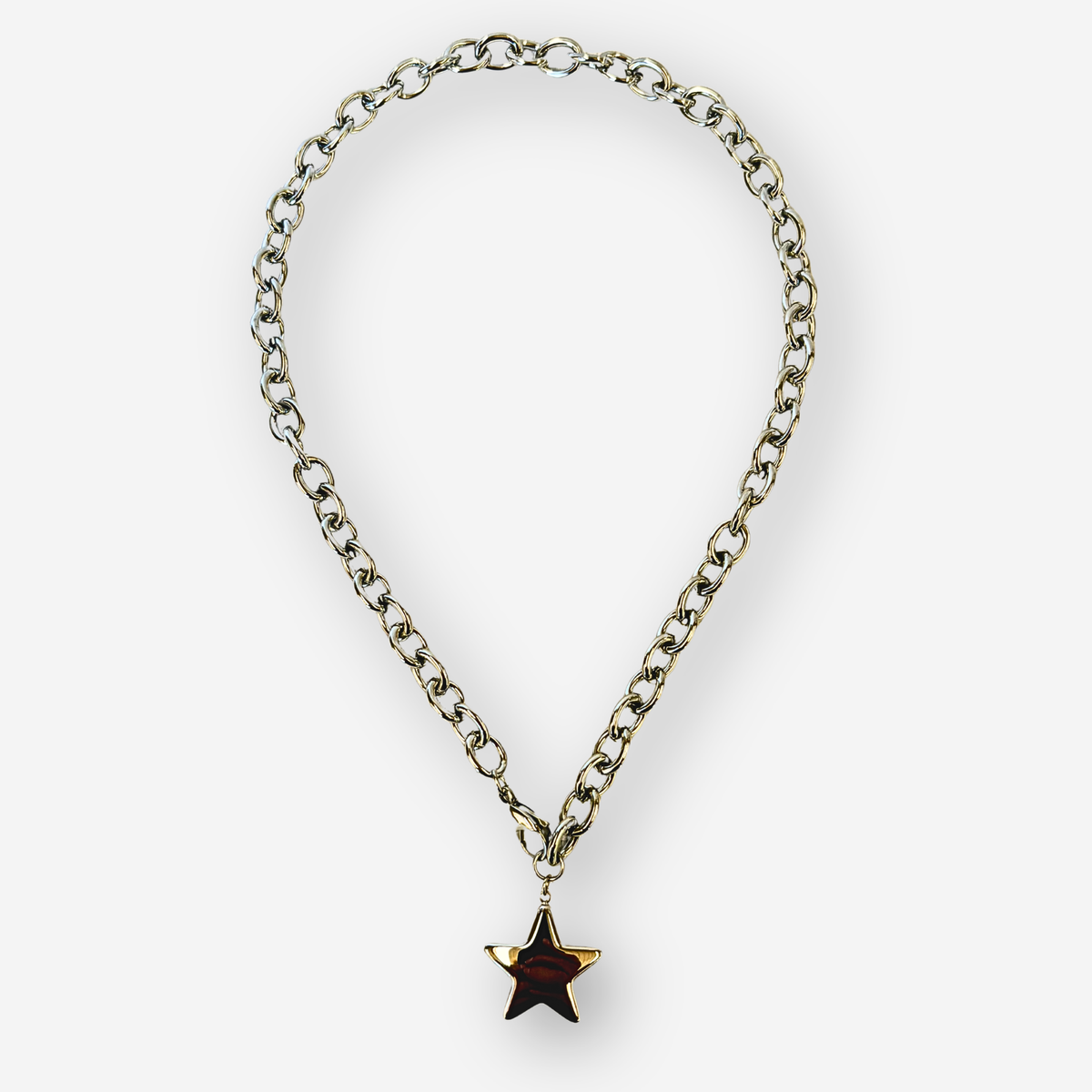 A silver-toned metal chain necklace with a dangling star-shaped pendant, set against a plain light gray background.