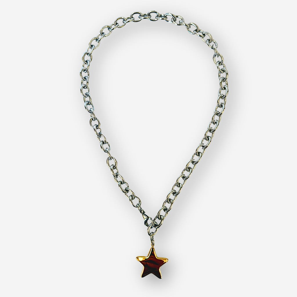 A silver-toned metal chain necklace with a dangling gold star-shaped pendant, shown on a light gray background.