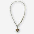 A silver chain necklace with a heart-shaped pendant featuring a sunburst pattern, displayed on a light gray background.