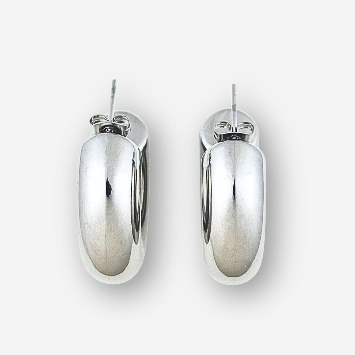 Large chunky silver hoop earrings on a light grey background