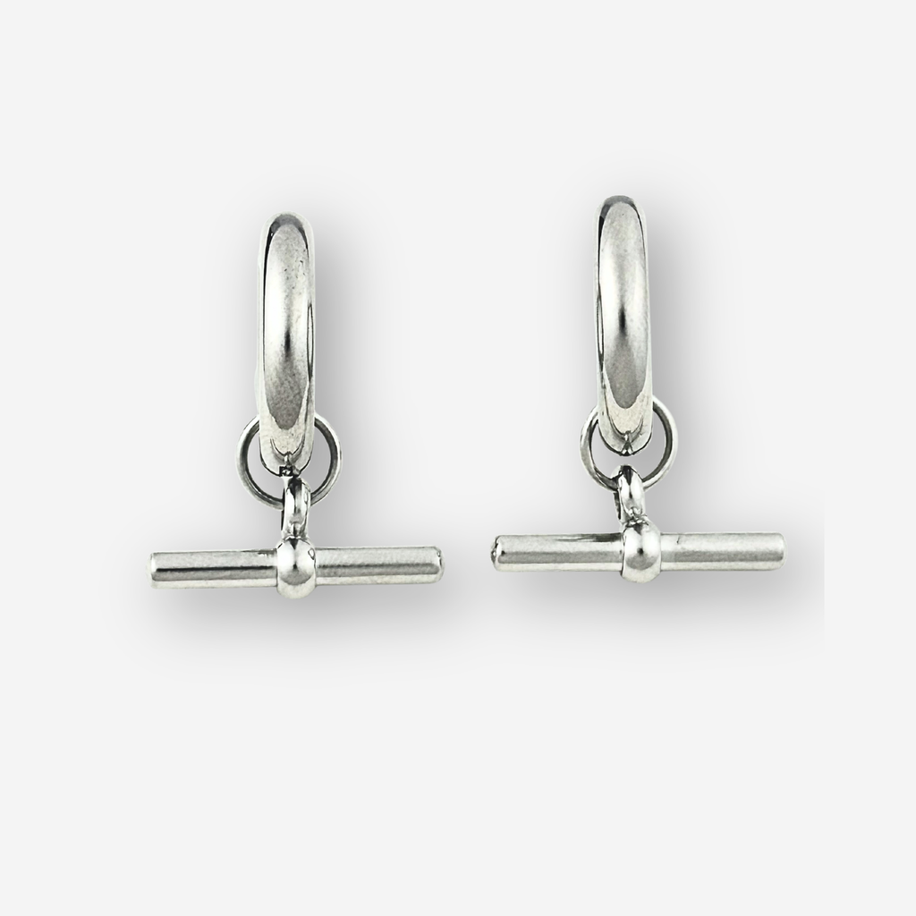 A pair of polished silver huggie hoop earrings with a toggle bar clasp, displayed on a clean light gray background.