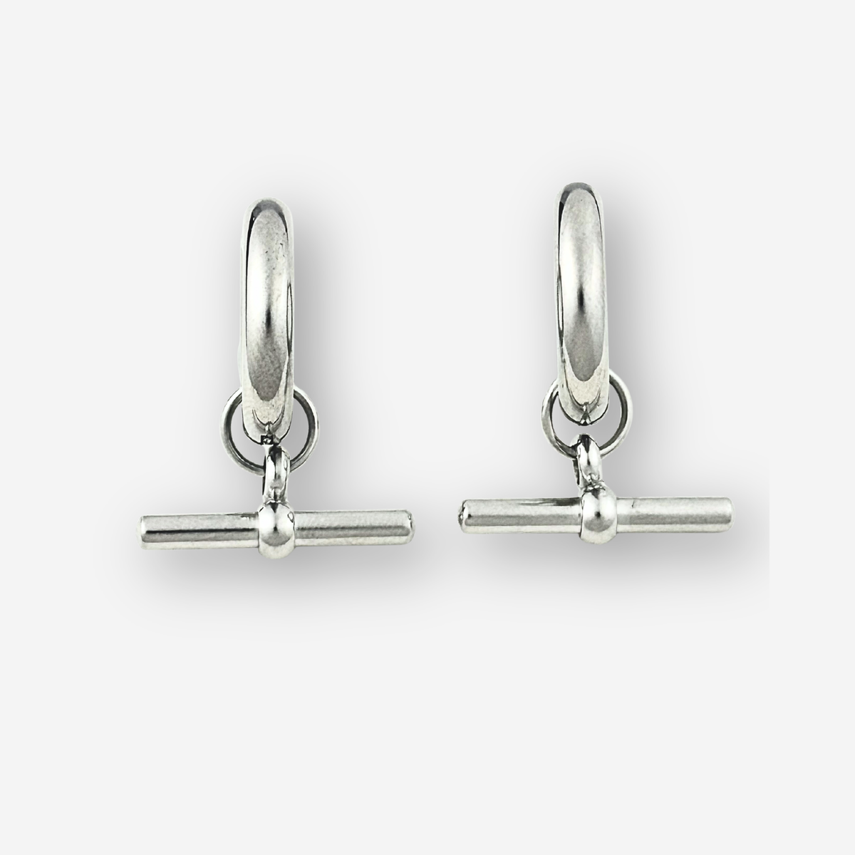 A pair of polished silver huggie hoop earrings with a toggle bar clasp, displayed on a clean light gray background.
