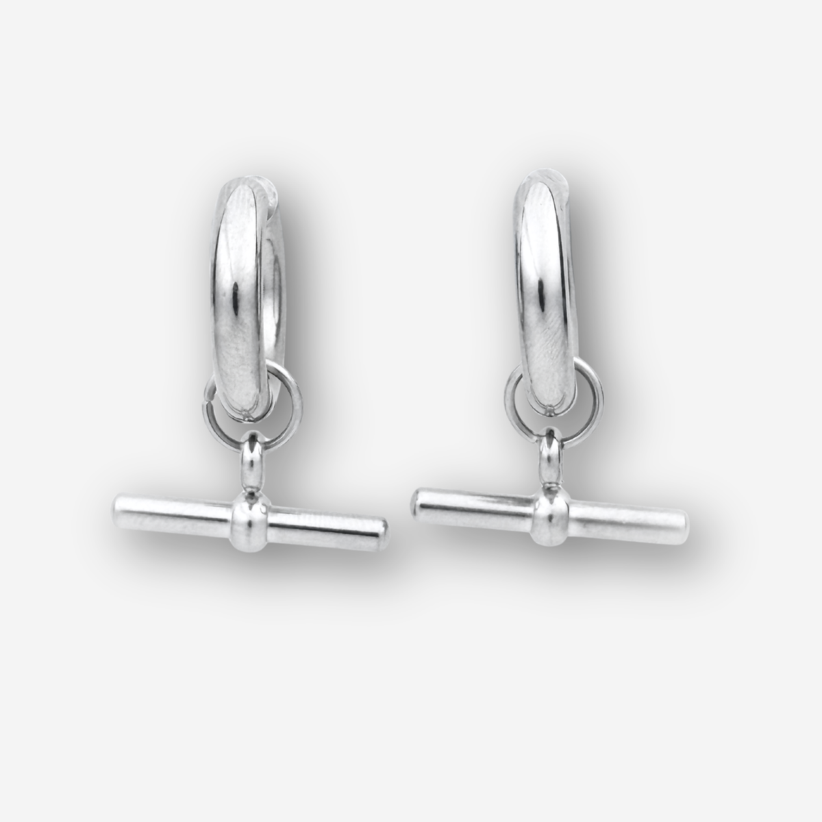 A pair of polished silver huggie hoop earrings with a toggle bar clasp, displayed on a clean light gray background.