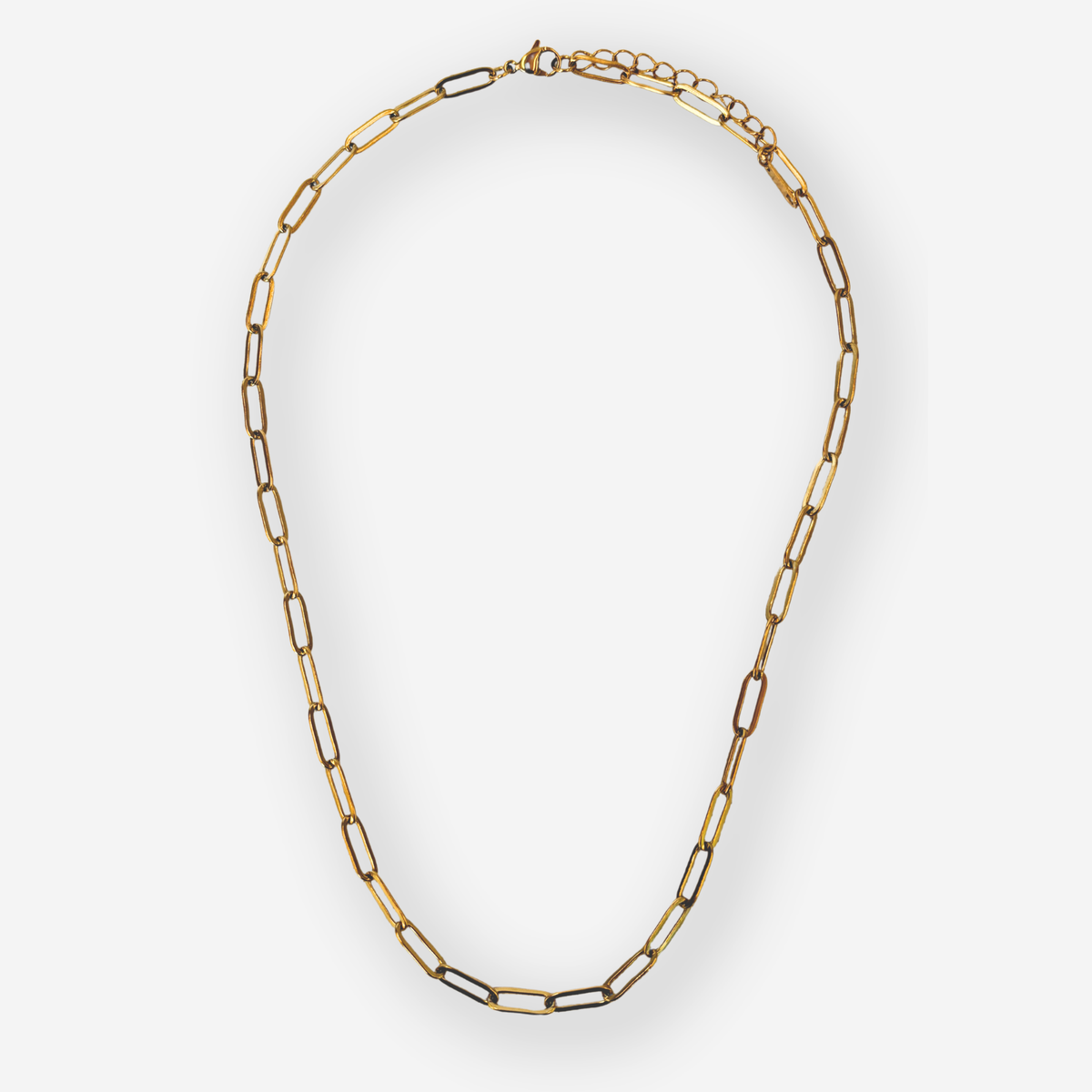 A gold paperclip chain necklace displayed on a clean light gray background.
