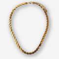 A gold chain necklace with a distinctive textured, overlapping leaf or oval link design, shown against a light gray background.