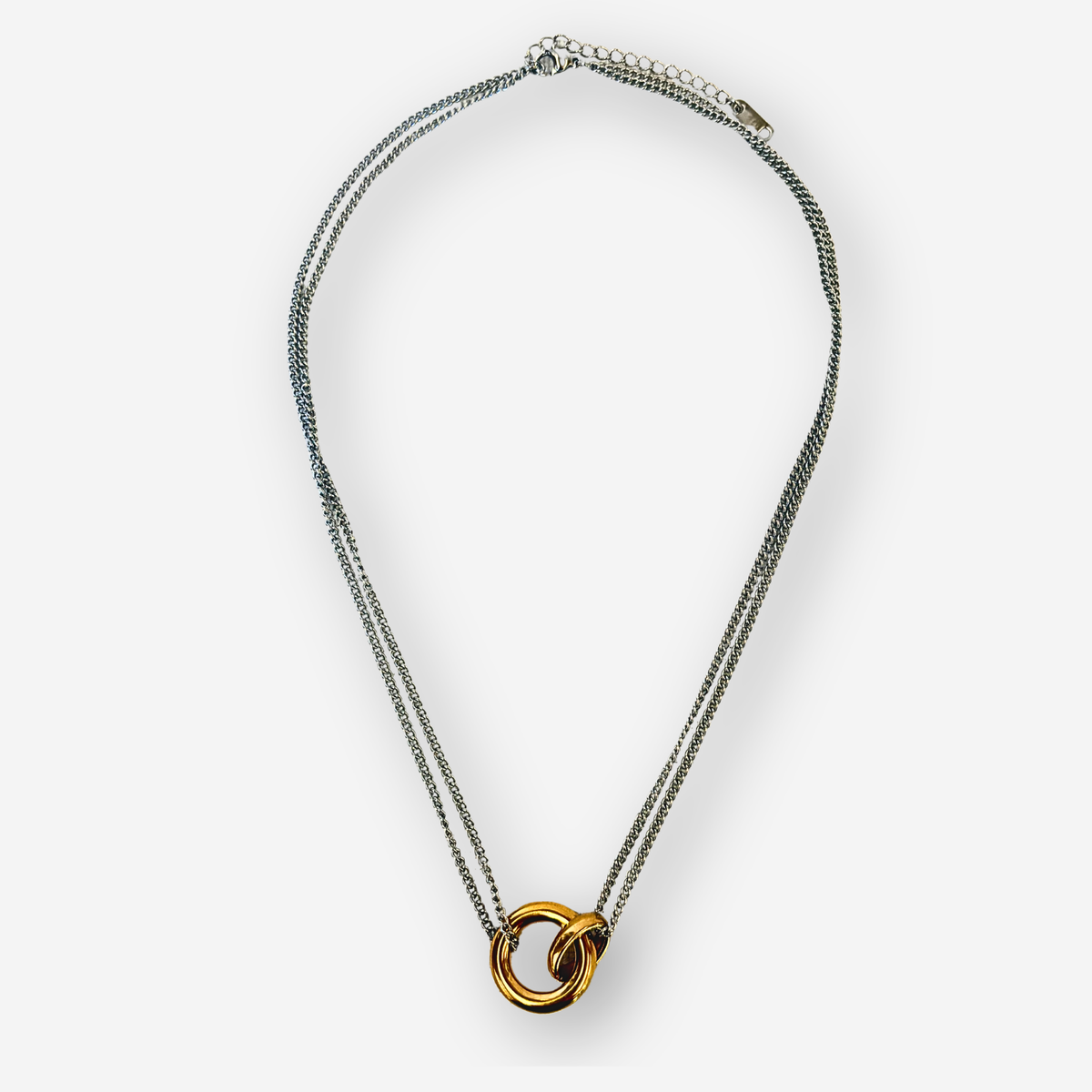 A double-strand silver-tone chain necklace with a central interlocking gold ring pendant, displayed on a clean light gray background.