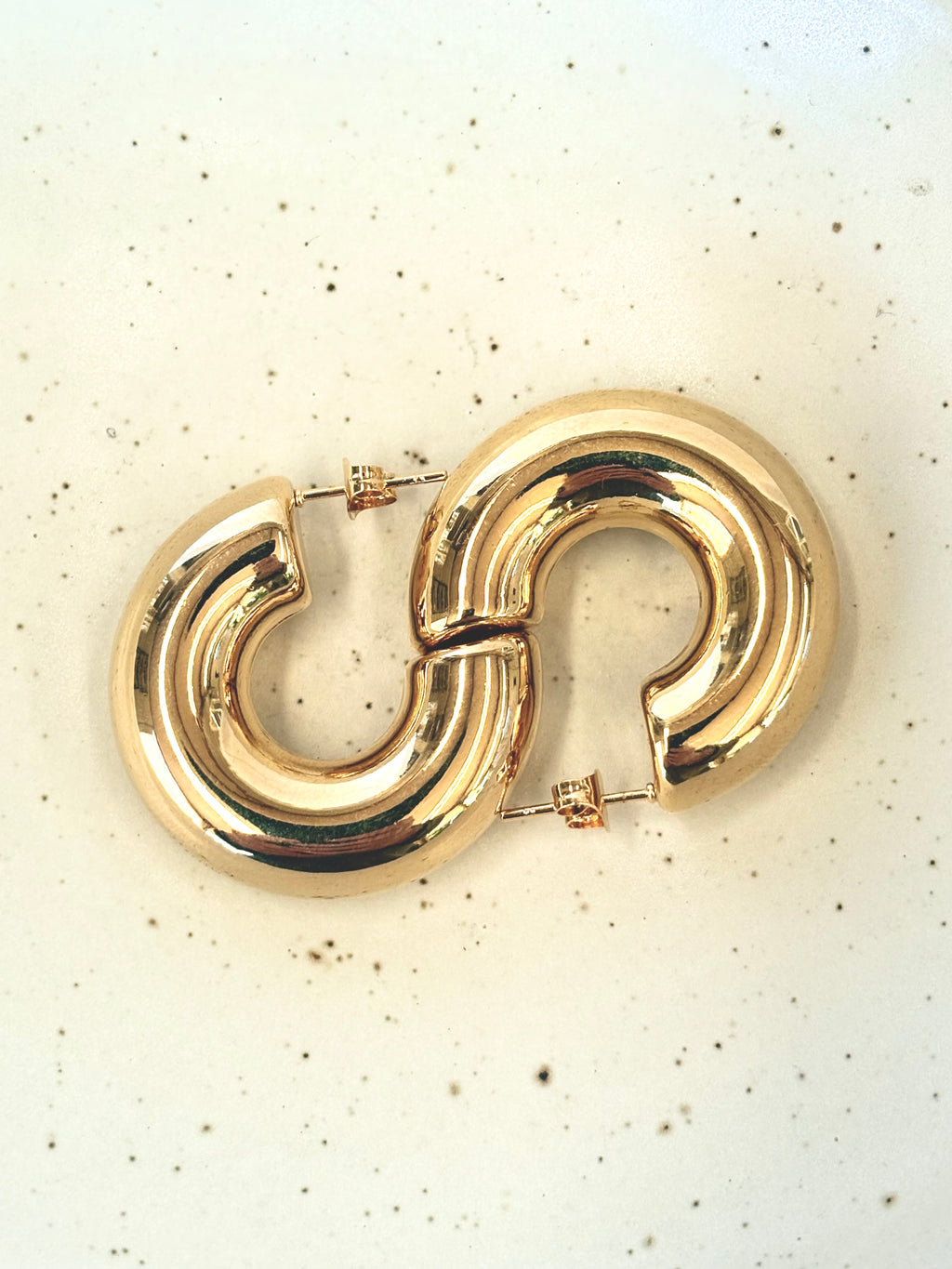 Gold hoop earrings on a light speckled background