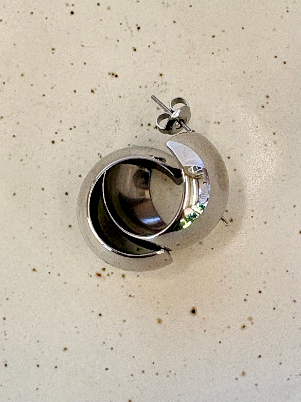 Silver earring on a beige background