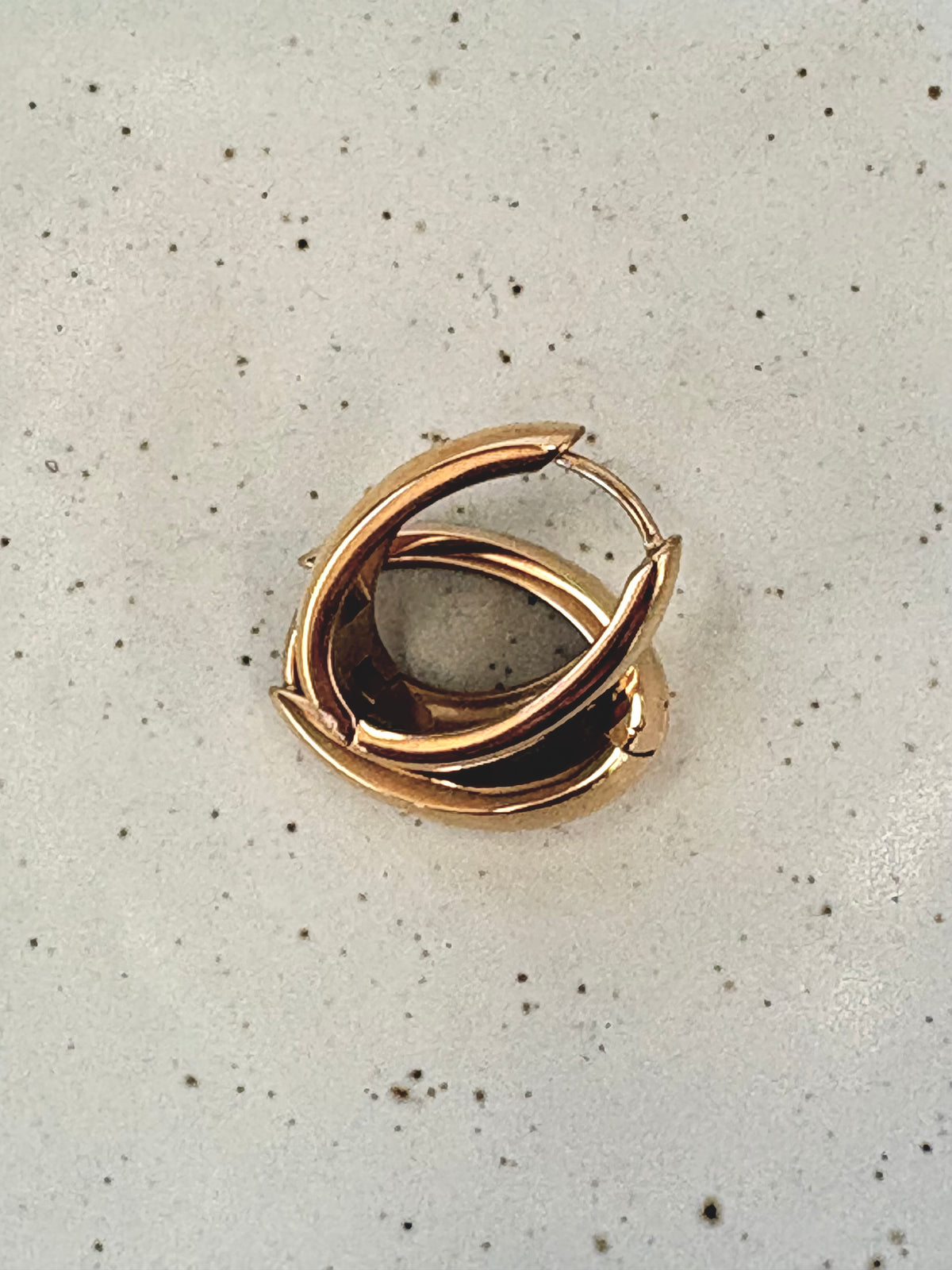 Gold spiral earring on a speckled gray background