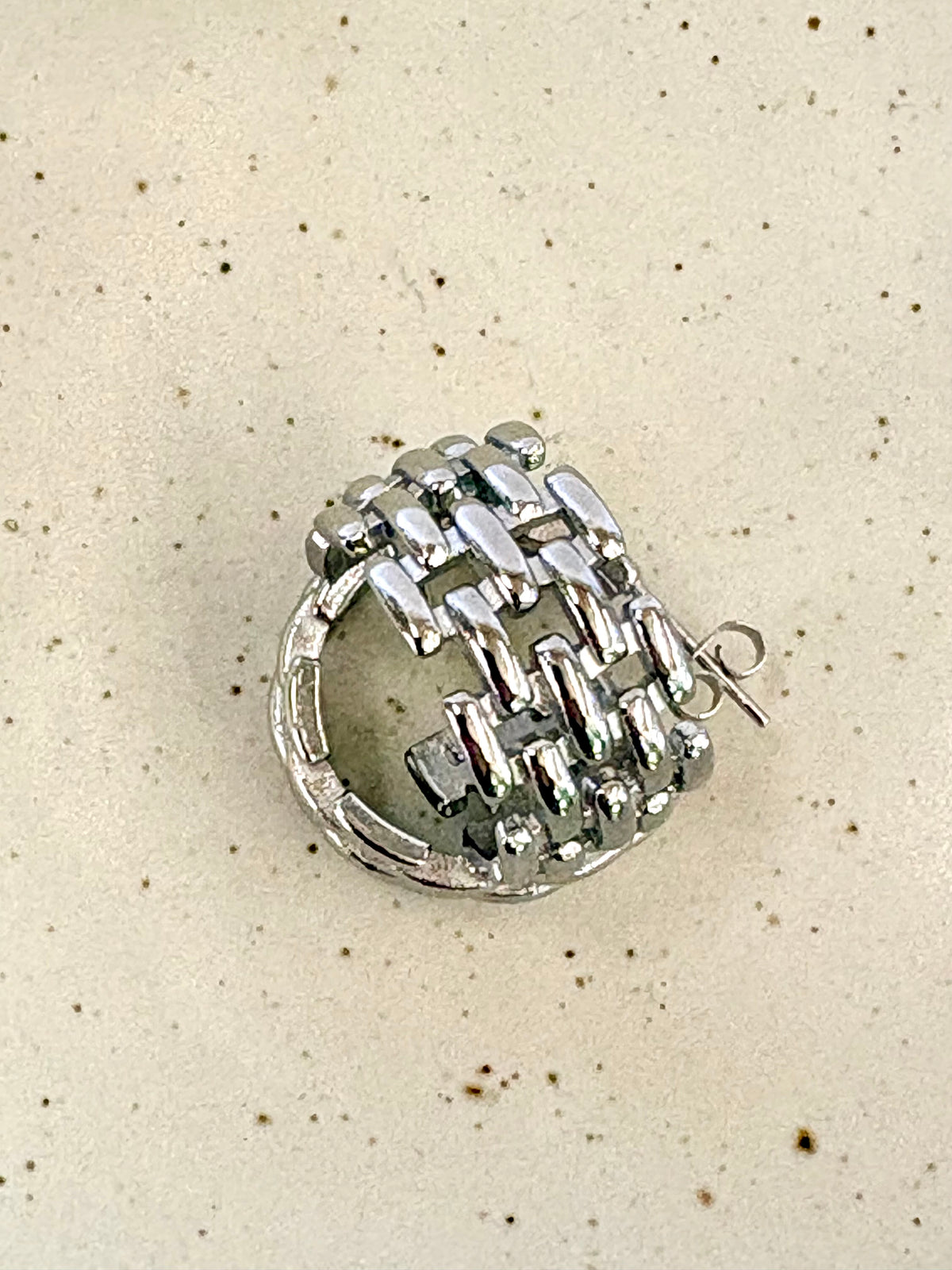 Silver ring with intricate design on a beige background