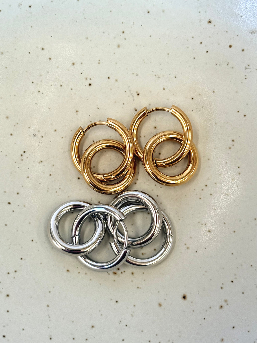 Double circle gold and silver hoop earrings on a light grey background