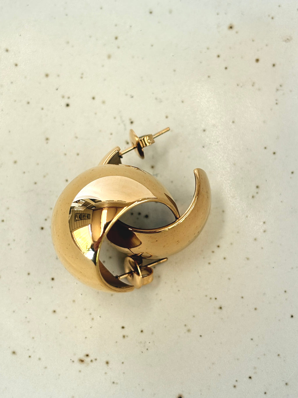 Gold hoop earring on a light speckled background
