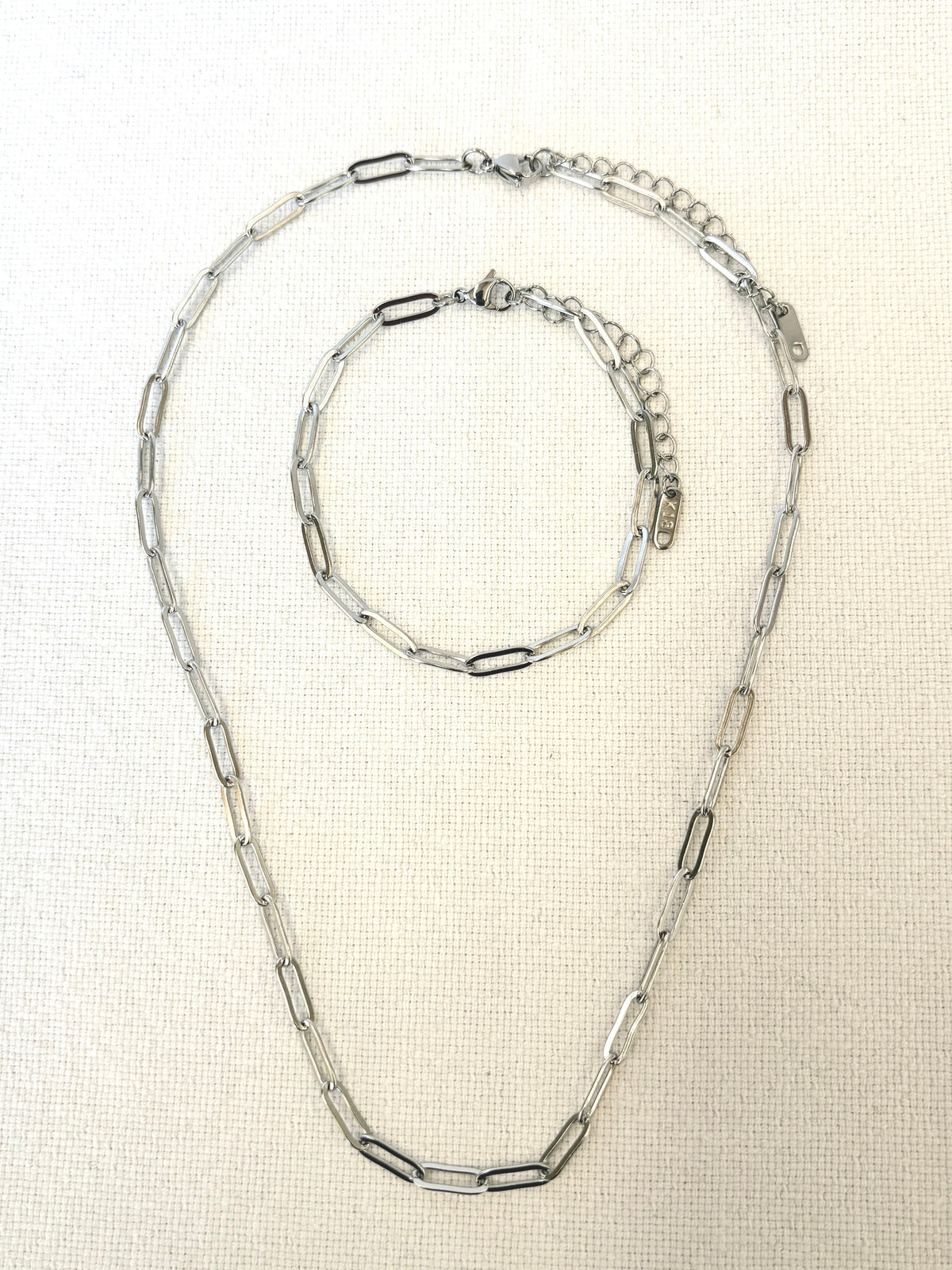 Sienna Paperclip Chain Silver Bracelet and necklace on light beige background