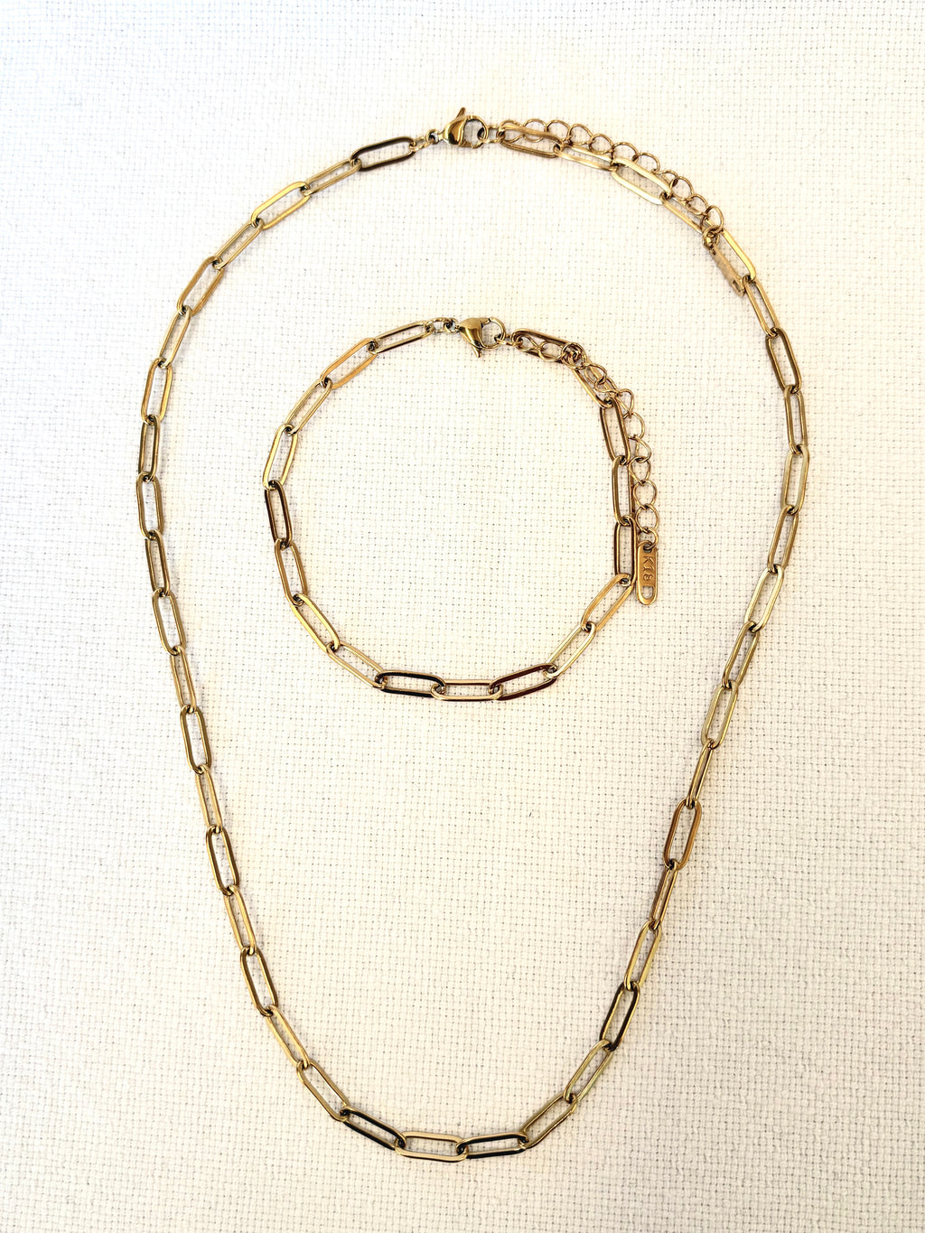 Sienna Paperclip Chain Gold Bracelet and necklace on textured beige background