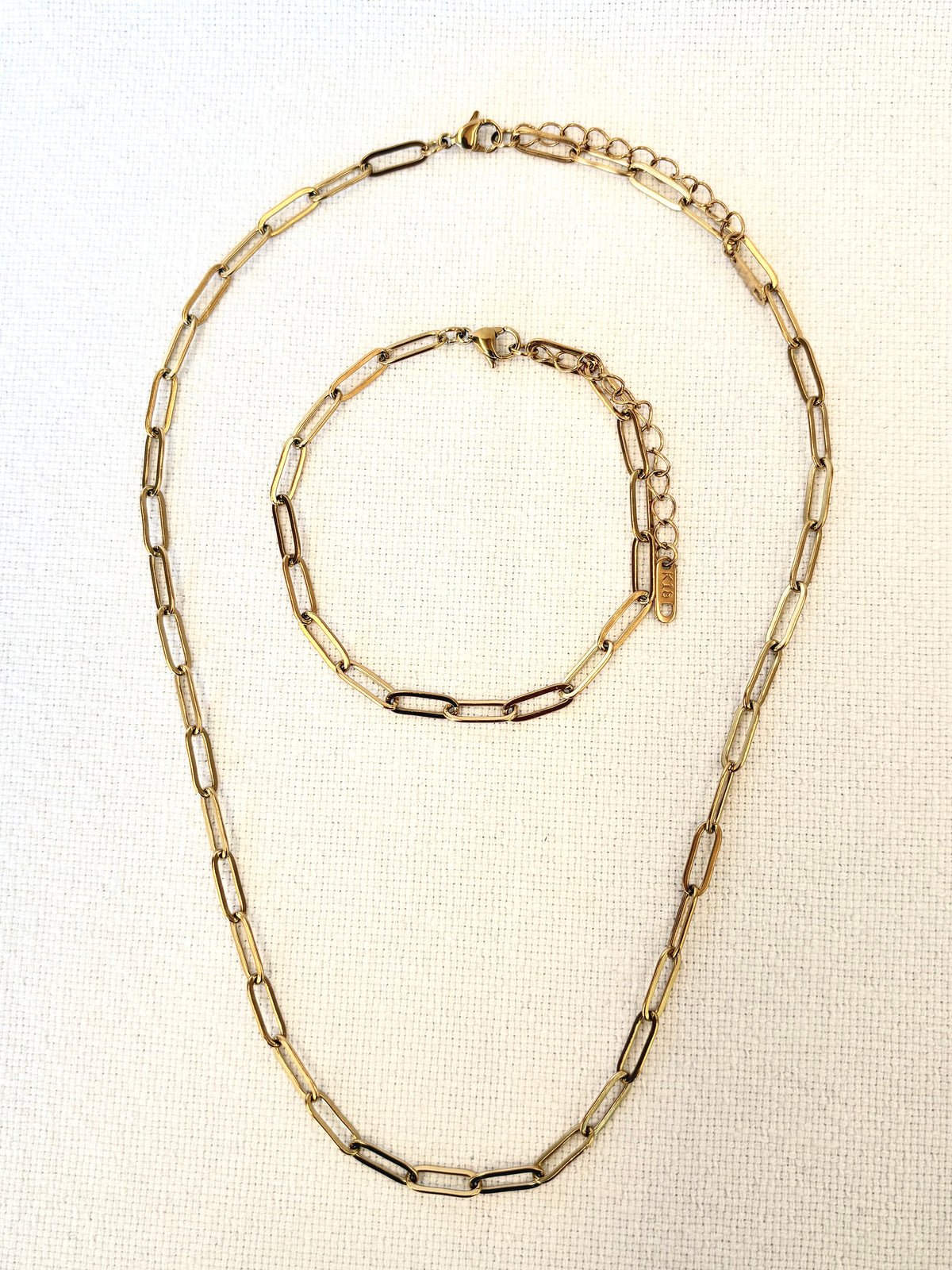 Sienna Paperclip Chain Gold Bracelet and necklace on textured beige background