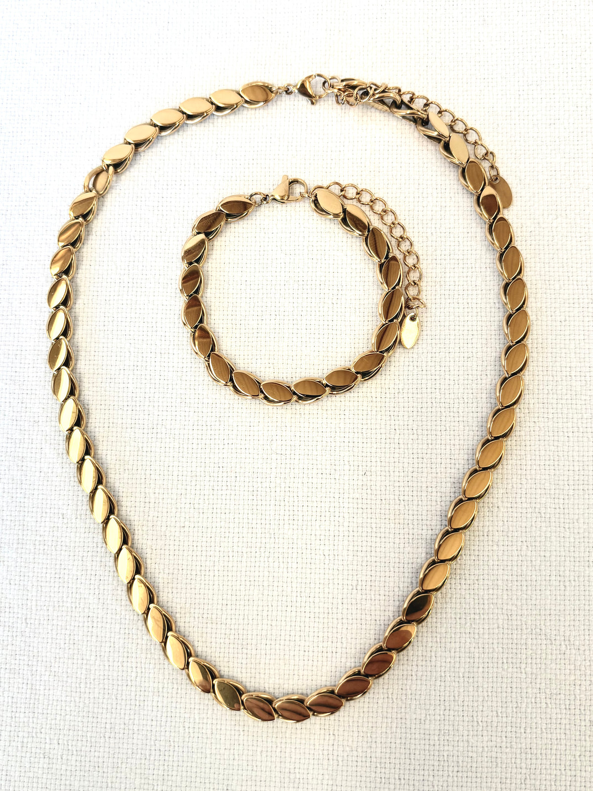Gold necklace and bracelet set on a white background