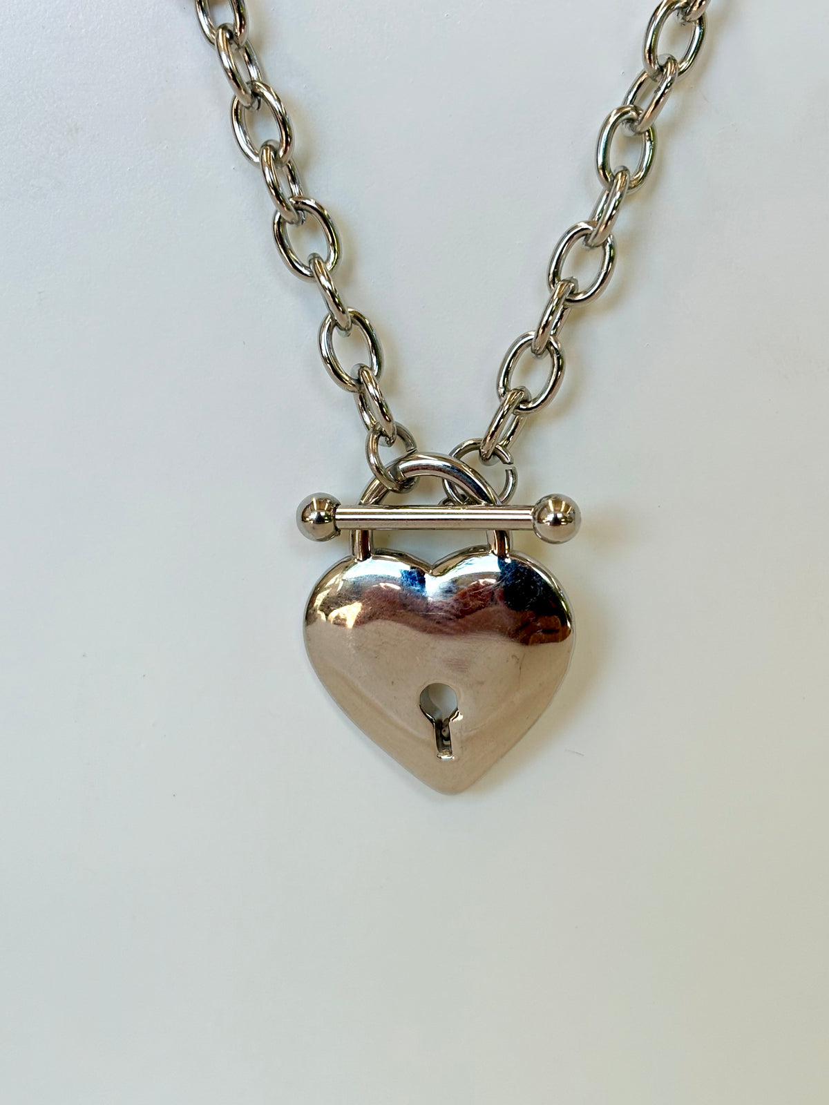 Silver heart-shaped padlock necklace on a white background