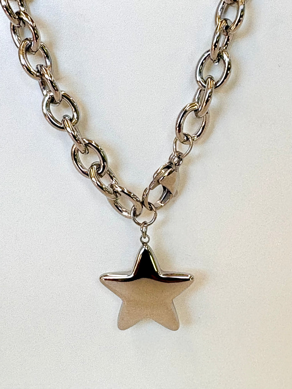 Silver chain necklace with a star pendant on a white background