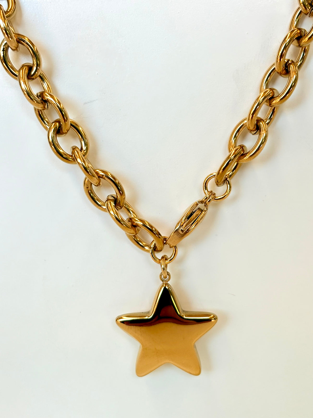 Gold chain necklace with a star pendant on a white background