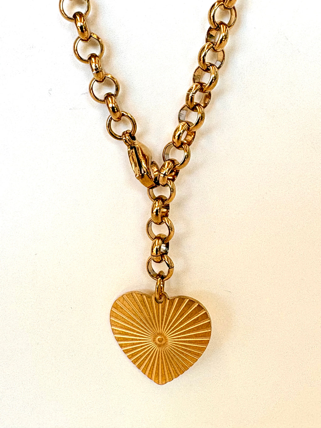 Gold chain necklace with a heart-shaped pendant on a white background