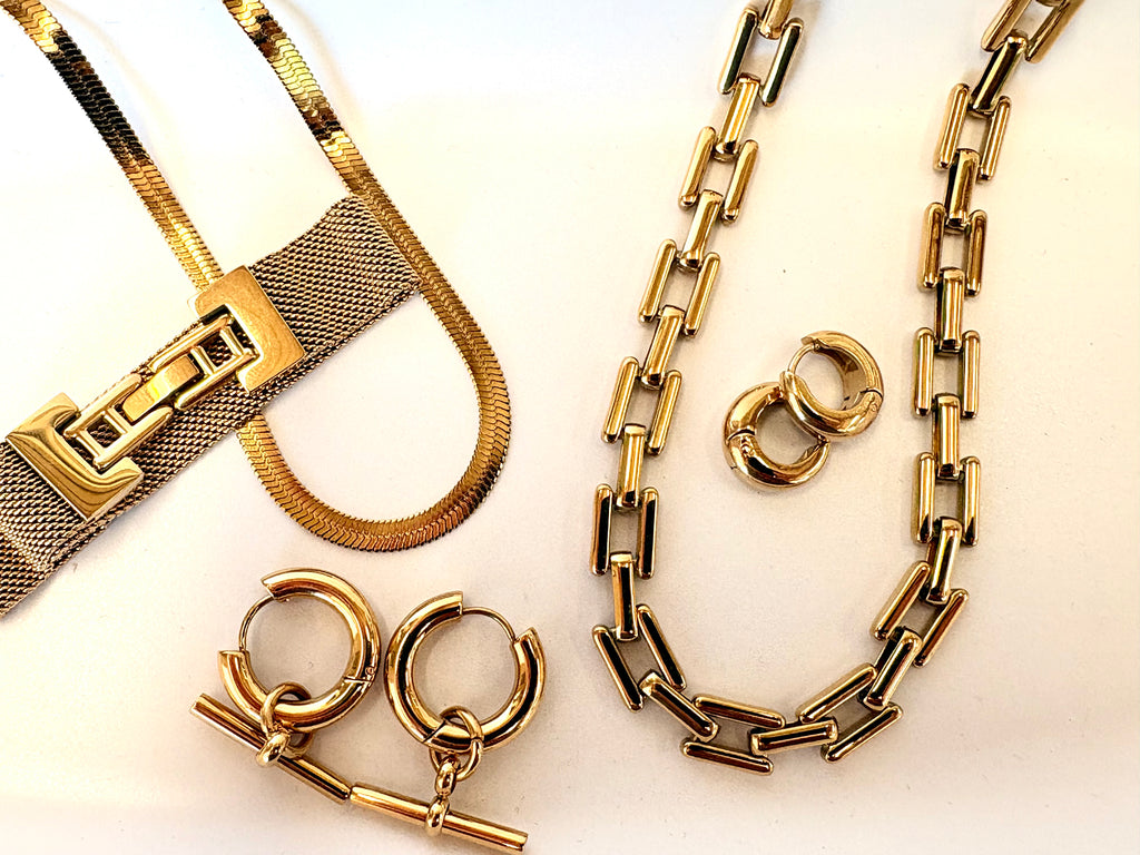 Gold jewelry including a necklace, bracelet, and earrings on a light background