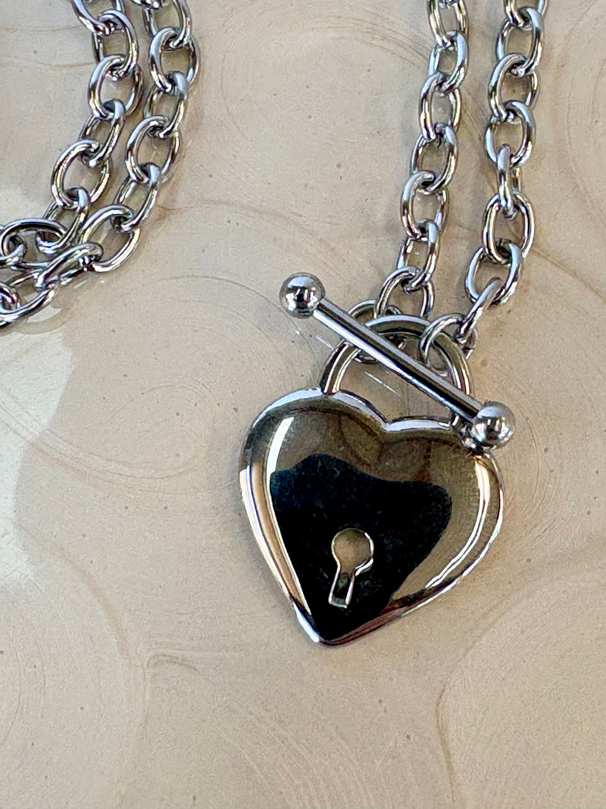 Heart-shaped lock pendant on a chain against a wooden background