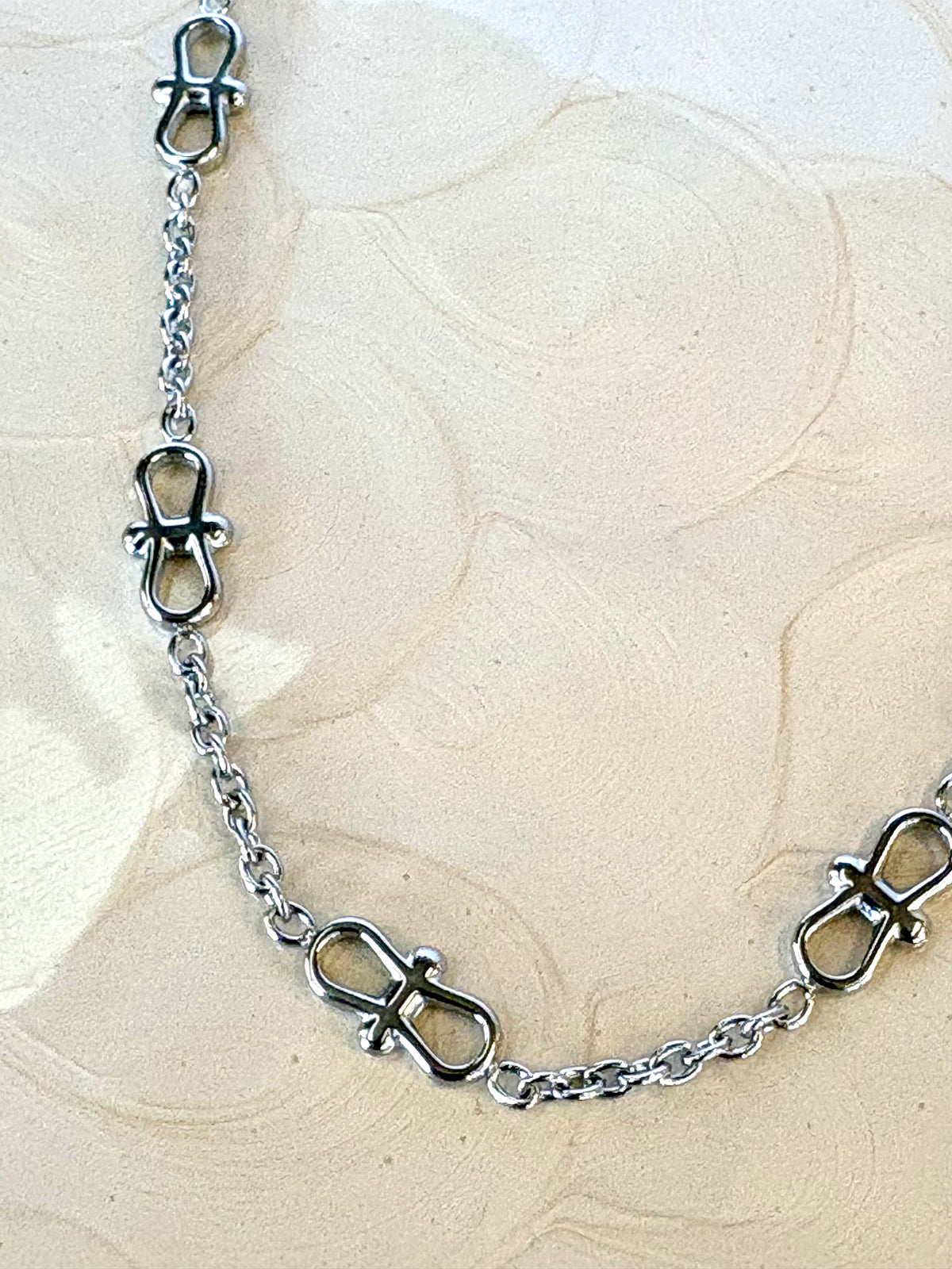 Silver chain bracelet on a textured beige surface