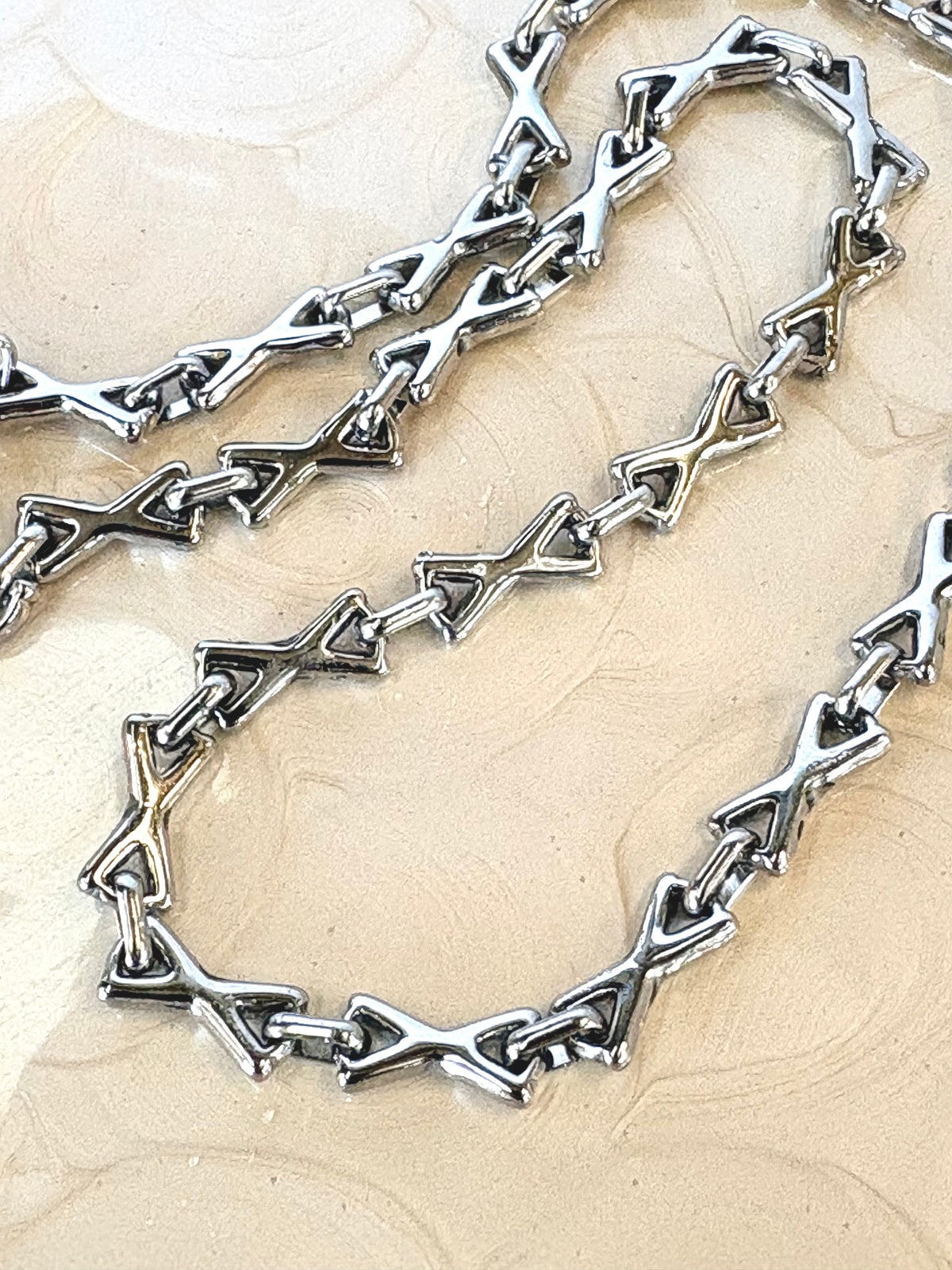 Silver chain necklace on a beige textured background