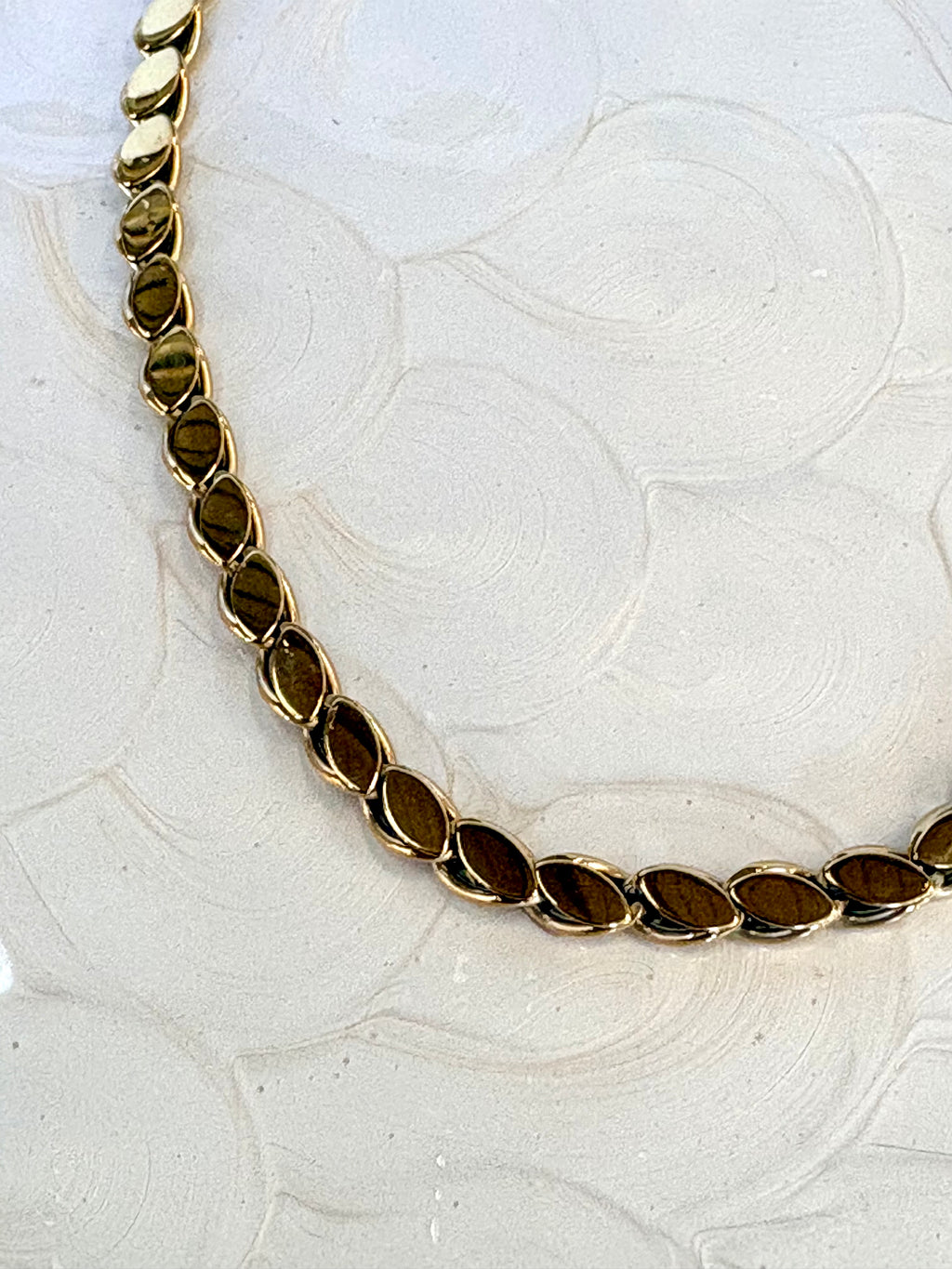Gold chain necklace on a textured white background