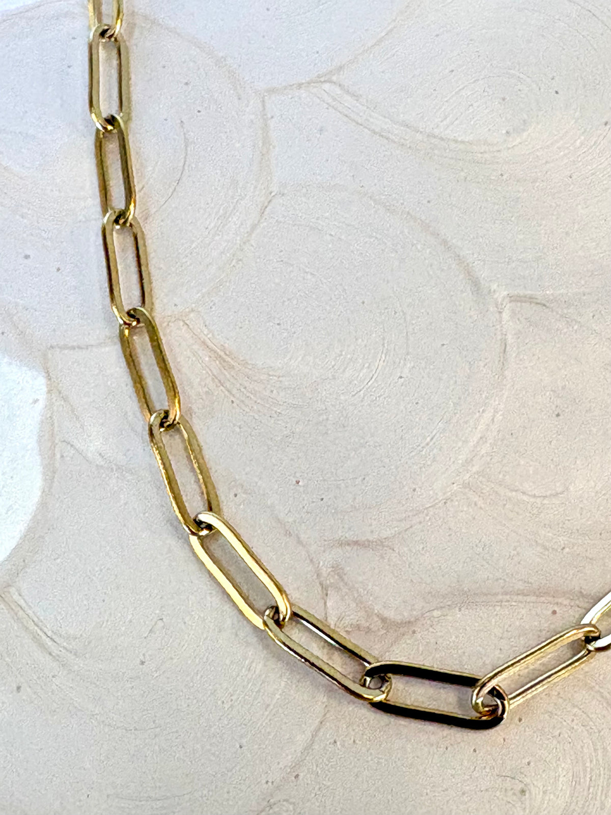Gold chain necklace on a textured white surface