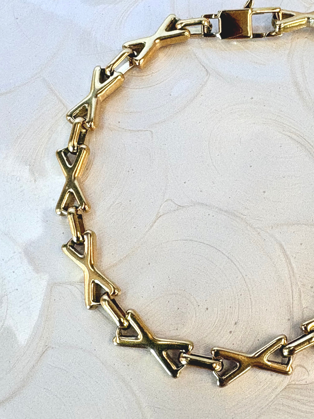XOXO Gold Bracelet flat lay on neutral background