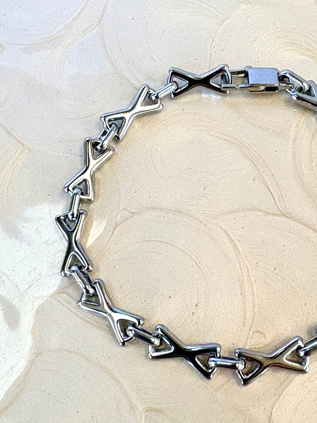 XOXO Silver Bracelet flat lay on neutral background