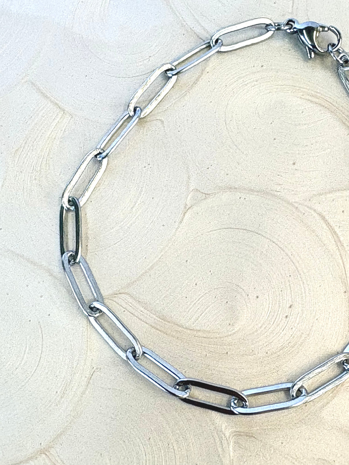 Sienna Paperclip Chain Silver Bracelet flat lay on neutral background