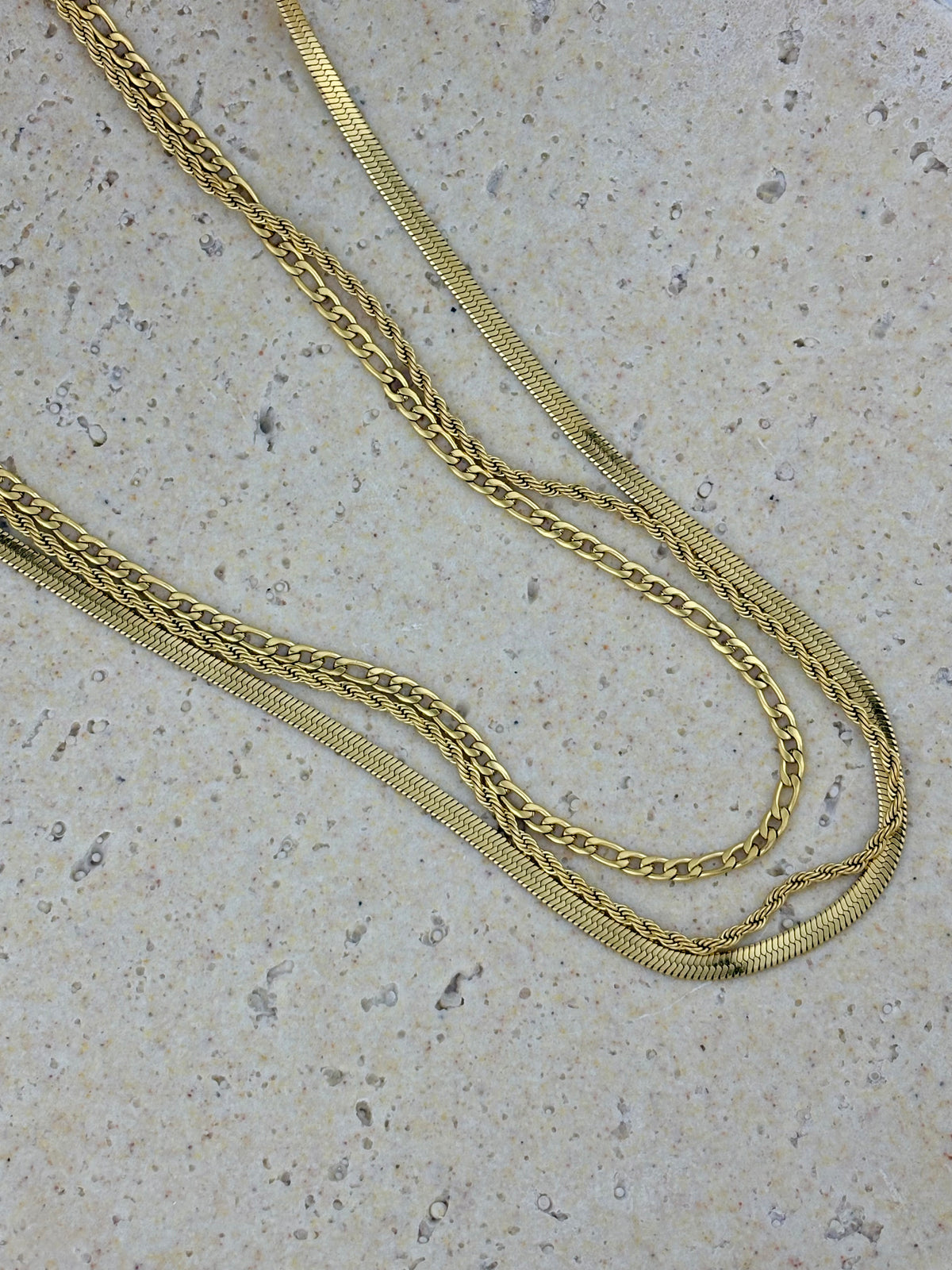 3 strand Gold chain necklace on a textured surface