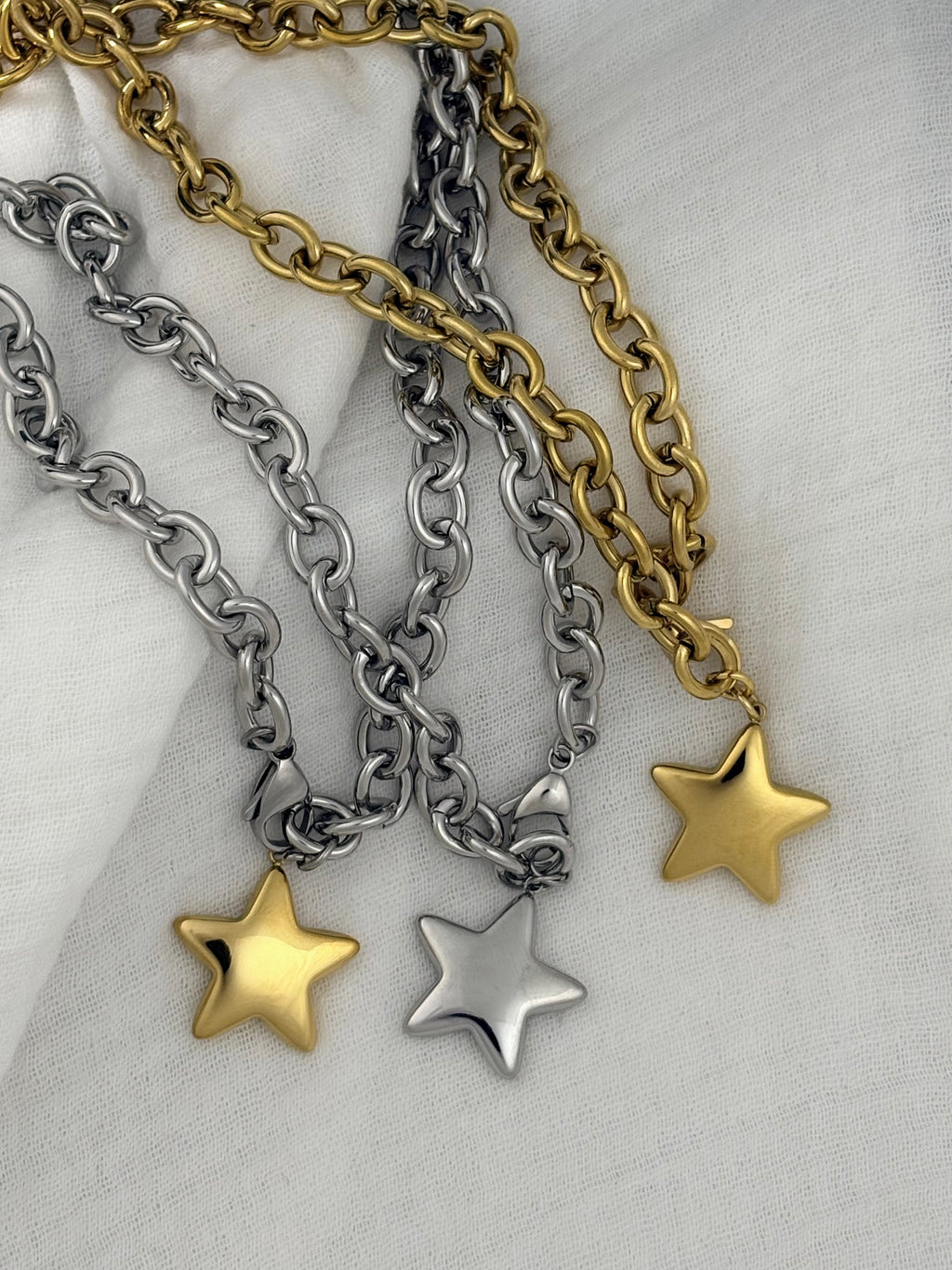 Three chain necklaces with star pendants on a textured surface