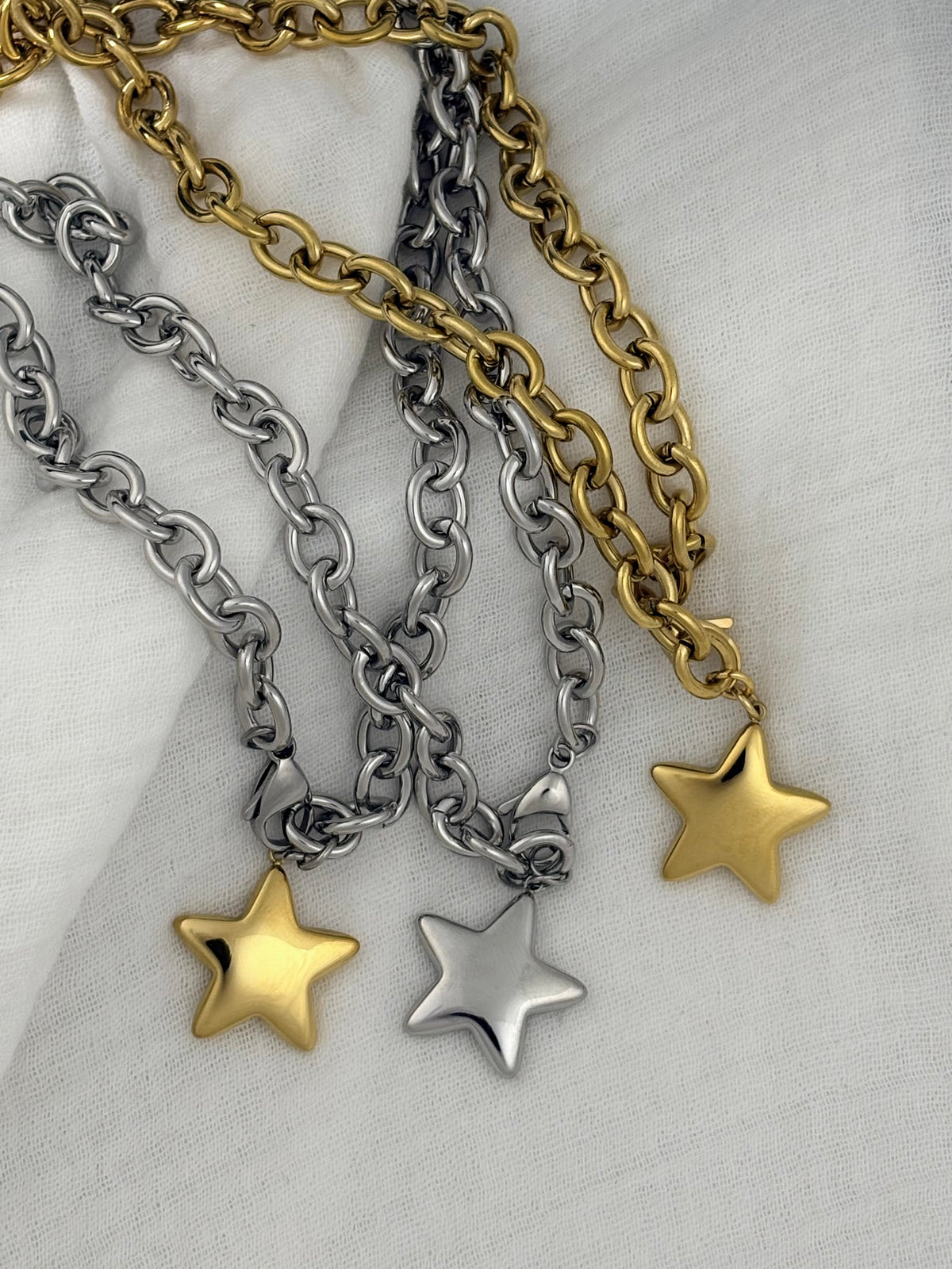 Three chain necklaces with star pendants on a textured surface