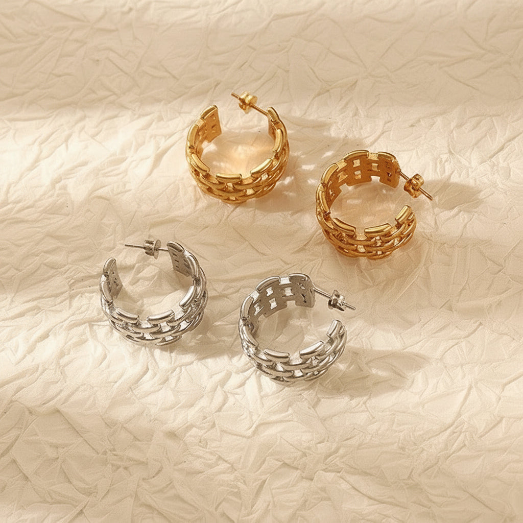 Gold and silver hoop earrings on a textured beige surface with yellow flowers.
