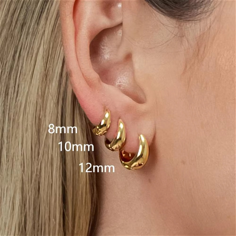Gold hoop earrings on an ear with size labels