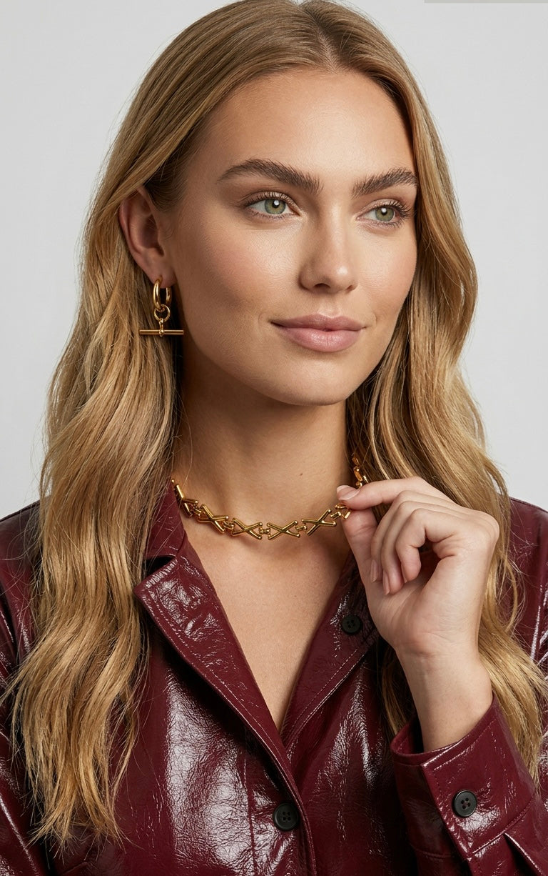 Woman wearing a gold necklace and earrings against a plain background